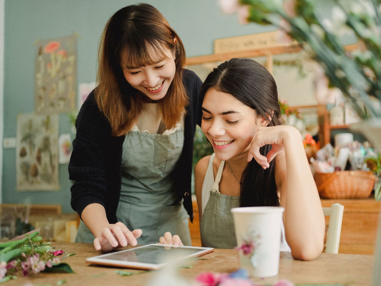 Two florists smiling at a tablet in their shop