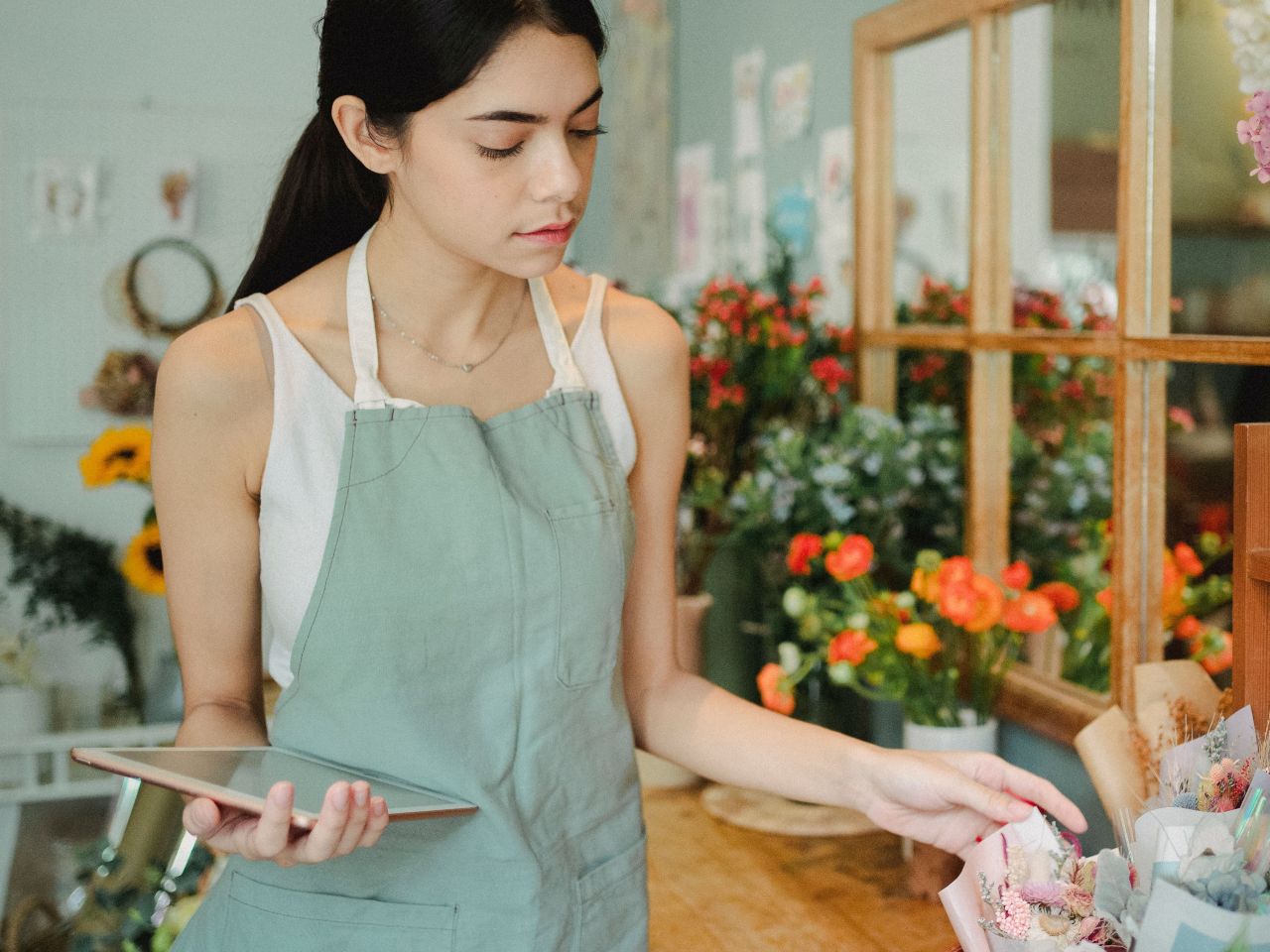 A florist holding a tablet in her flower shop